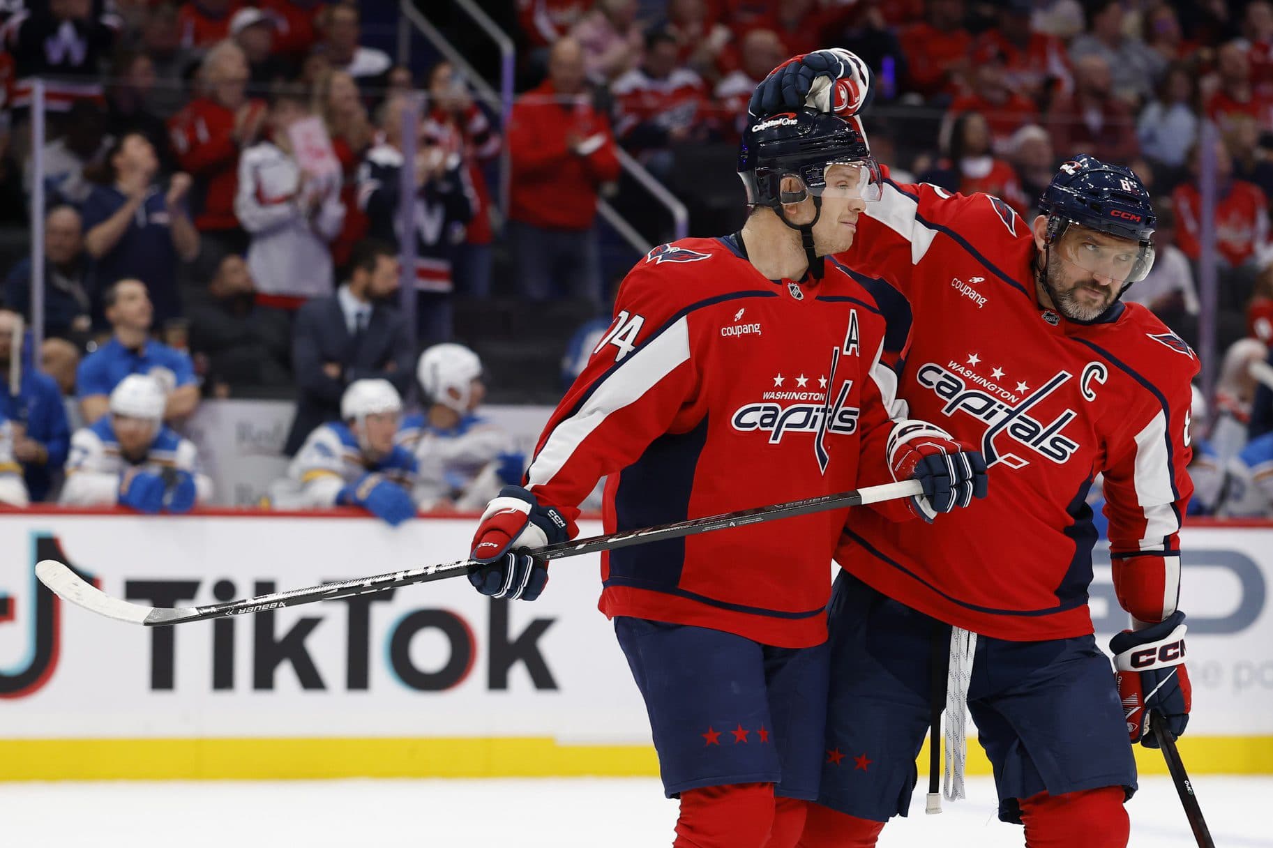 Washington Capitals defenseman John Carlson (74) is congratulated by Capitals left wing Alex Ovechkin (8) while being recognized for his 1,100th NHL point during a timeout against the St. Louis Blues during the first period at Capital One Arena.