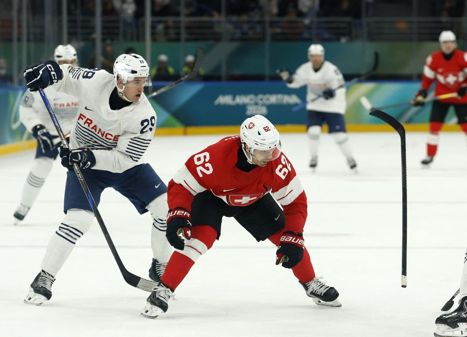 Louis Boudon of France knocks the stick from the hands of Denis Malgin of Switzerland during a Group A men's ice hockey game during the Milano Cortina 2026 Olympic Winter Games at Milano Santagiulia Ice Hockey Arena.